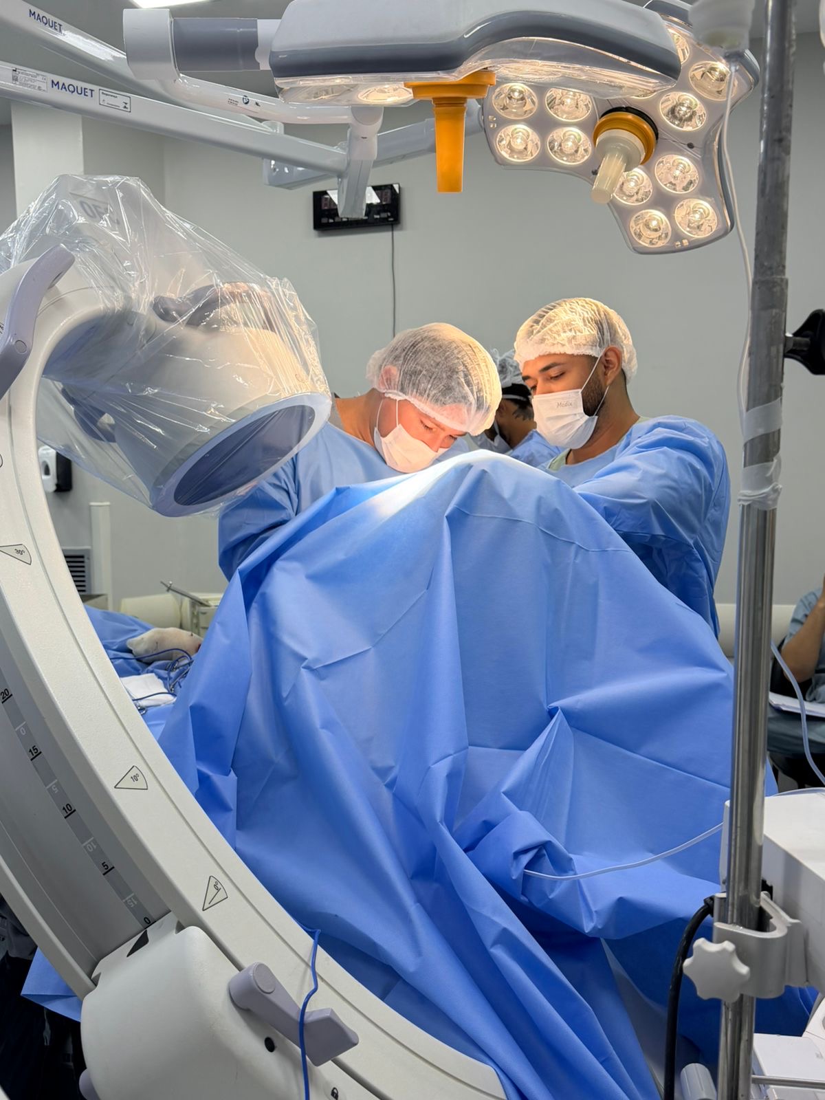 Equipe durante cirurgia do ombro com auxílio de equipamento de fluoroscopia.
